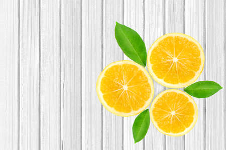 yellow fresh lemon fruit slices with green leaves on the white wooden table  backgroundの写真素材