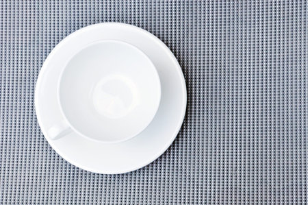 White tea cup and plate on gray cloth table, top viewの写真素材