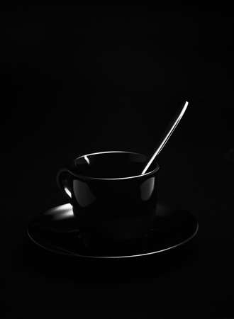 Black cup with high-grade steel spoon in front of black backgroundの写真素材