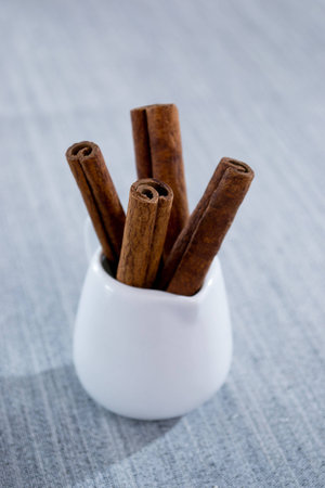 Cinnamon sticks in a glass of white on a blue background