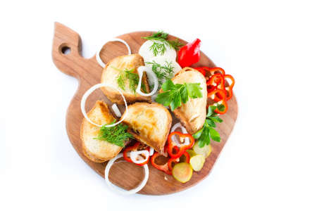 Hot sandwich with sausage, cheese, onion and herbs on a wooden board on a white backgroundの写真素材