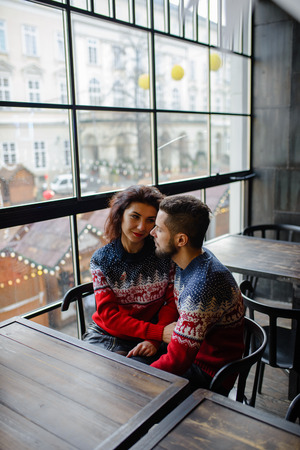 Happy charming woman dressed in knitwear talking to her handsome boyfriend spending time at cozy home, romantic couple in love happy about being together celebrating winter holidays in good moodの写真素材