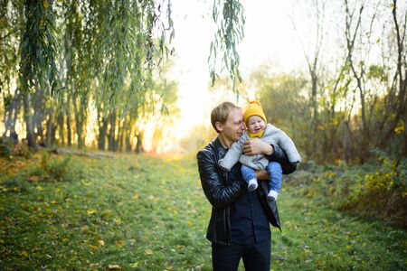 Happy smiling Caucasian father dad with cute adorable baby girl. Family in autumn fall park outdoor with yellow orange leaves trees.の写真素材