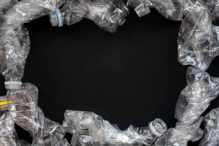 Mock up on the theme of environmental protection. Compressed plastic bottles on a black background.の写真素材