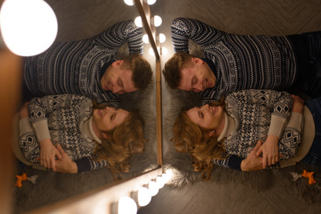 A couple in love in knitted sweaters lie on the floor, hugging and kissing.の写真素材