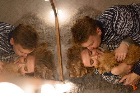 Beautiful couple relaxing at home and loving their pet.A loving couple lies on the floor and hugs.の写真素材