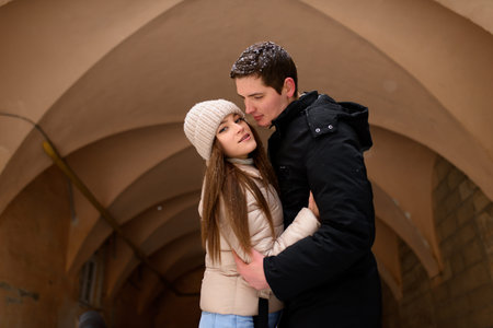 Young couple kissing under a huge pine in a city covered with white snowの写真素材