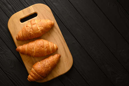 Freshly baked croissants with berries jam and butter, dark wooden background, selective focusの写真素材