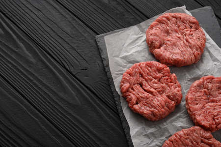 Raw Ground beef meat Burger steak cutlets on dark wooden background.の写真素材