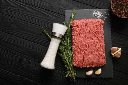 Fresh raw meat or ground chicken meat on a wooden cutting board with thyme, spices and garlic. Black wooden background. top view. copyspace.の写真素材