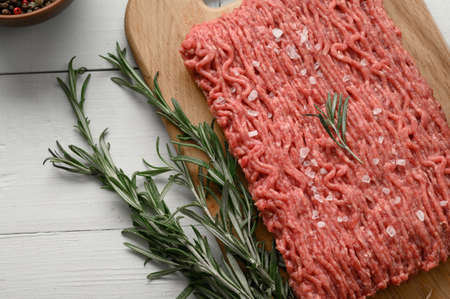 Fresh raw meat or ground chicken meat on a wooden cutting board with thyme, spices and garlic. White wood background. top view. copyspace.の写真素材