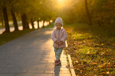 A girl in a pink jacket stands at sunset.の写真素材
