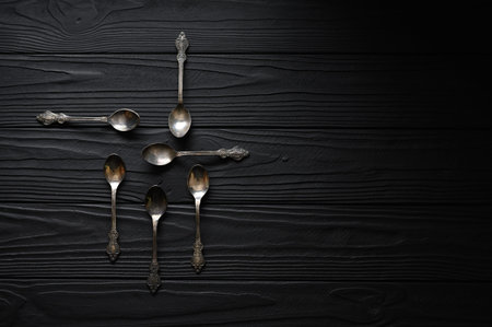 Directly above a shot of old spoons on a black tableの写真素材