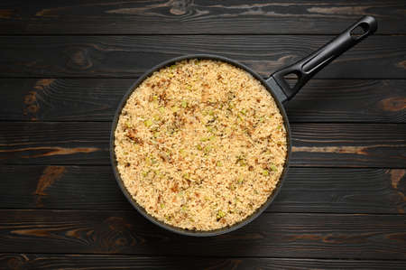 Fried rice with onions and zucchini in a pan on a rustic wooden background.の写真素材