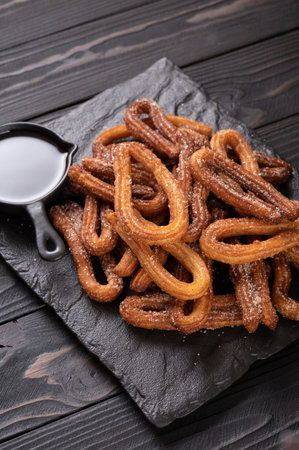 Homemade churros with chocolate on a dark wooden rustic background.の写真素材