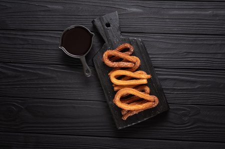 Homemade churros with chocolate on a dark wooden rustic background.の写真素材