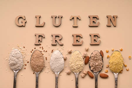 Gluten free text and spoons of various gluten free flour, almond buckwheat, rice, corn, oat, chickpea. Flat lay, top.の写真素材