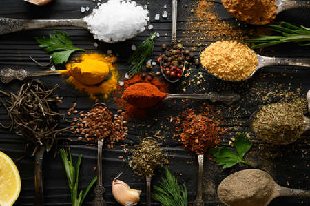 Colorful various herbs and spices for cooking on dark wooden rustic backgroundの写真素材