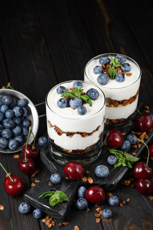 Homemade layered dessert with fresh blueberry, cherry, cream cheese or yogurt, granola.の写真素材