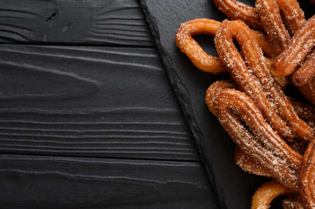 Homemade churros on a wooden black background.の写真素材