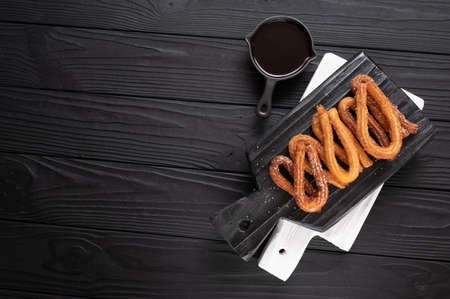 Homemade churros with chocolate on a dark wooden rustic background.の写真素材