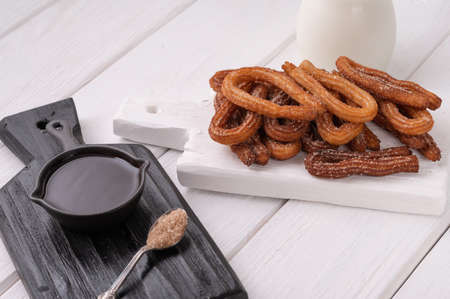 Homemade churros with chocolate on a white wooden background.の写真素材