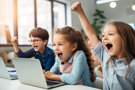 Cheerful schoolkids looking at laptop screenの素材