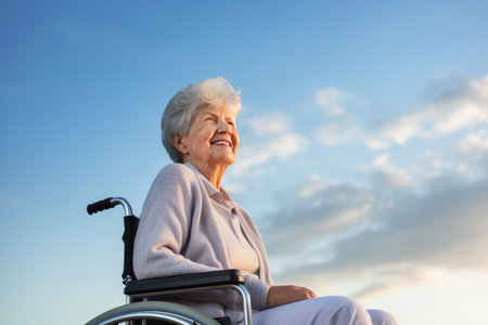 portrait of a smiling senior woman in wheelchair outdoor blue sky backgroundの素材
