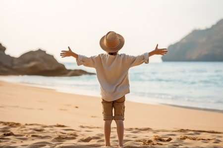 a boy 10 years old jump with his arms outstretched on the beachの素材