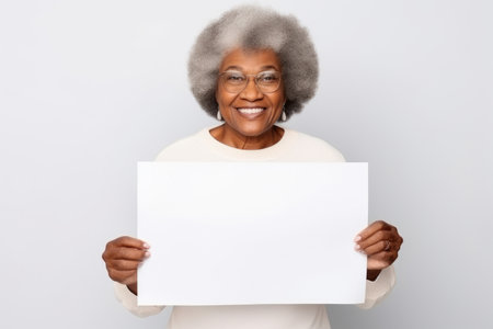 Happy old black woman holding blank white banner sign, isolated studio portraitの素材