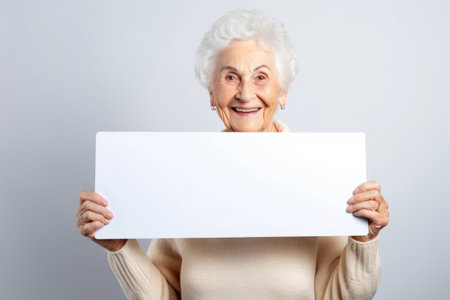 Happy old woman holding blank white banner sign, isolated studio portraitの素材