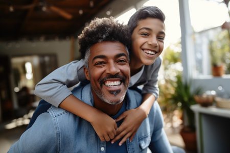 Happy African Black father having fun with teen boy at home.の素材