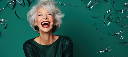 Happy Mature Woman with Gray Hair Celebrating New Years Party on an emerald Background with Space for Copyの素材