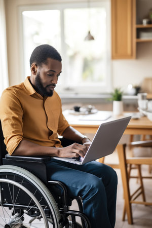 Black man with disability checking his medical documents and filling form on laptopの素材