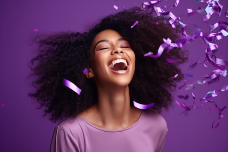 Energetic active African American lady dancing moving on holiday with flying confetti isolated on violet color backgroundの素材