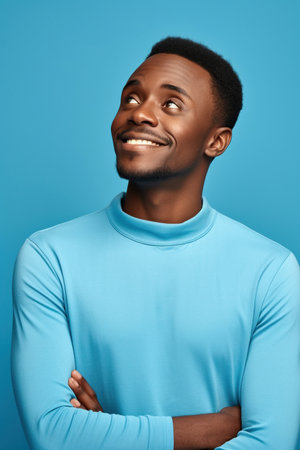 African American man thinking about his inspiration touch chin looking mockup choosing product option isolated on blue color backgroundの素材
