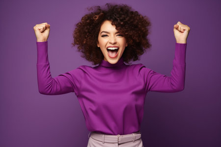 Overjoyed cheerful woman dressed stylish clothes celebrate success raise hands fists isolated on purple color backgroundの素材