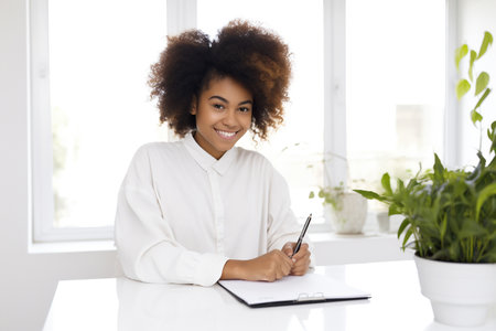 A smiling African American girl is writing on a tablet.の素材