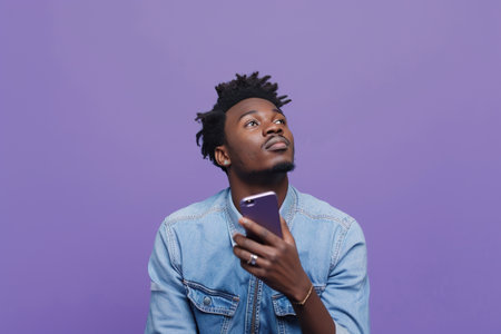 African American man with phone on purple studio backgroundの素材