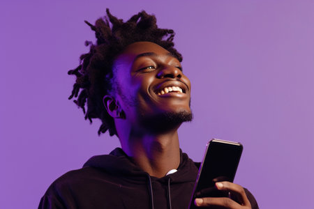African American man with phone on purple studio backgroundの素材