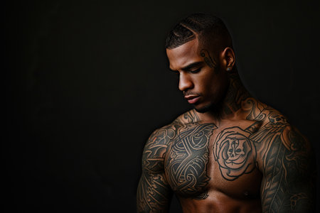 Confident African American man with muscular body tattooed on black background.の素材