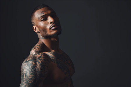 Confident African American man with muscular body tattooed on black background.の素材