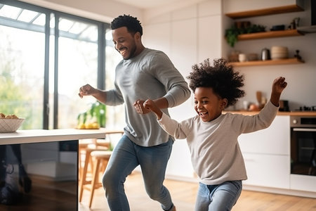 Happy african american family father and little son dancing on a kitchenの素材