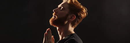 Man prays to god on black studio backgroundの素材