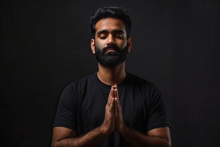 Indian man prays to god on black studio backgroundの素材