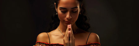 Latin American woman prays to god on black studio backgroundの素材