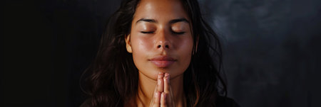 Latin American woman prays to god on black studio backgroundの素材
