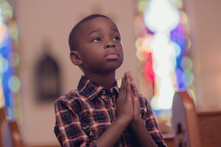 African American boy praying in churchの素材