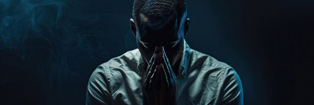 African American Man prays to god on black studio backgroundの素材