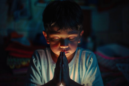 Latin American boy prays to god in dark children room. Cinematic effectの素材
